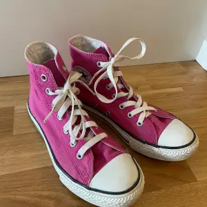 Säljer ett par klassiska rosa Converse All Star sneakers i storlek 35. De har en hög modell med vit snörning och den ikoniska loggan på sidan. Skorna är i textilmaterial och har en vit gummisula. Perfekta för sommar och hösten! knappt använda