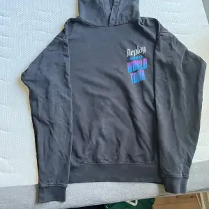 Säljer en svart hoodie från Replay med tryck '1990 World Tour' i blått och lila på både fram- och baksidan. Den har en cool design med en dödskalle och orm på baksidan. Hoodien är storlek L men passar även M. 