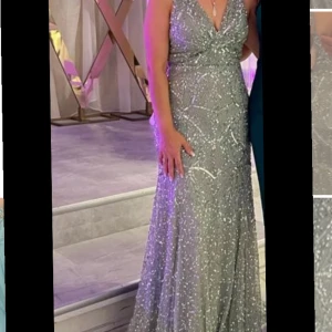 Glittrig långklänning - Säljer en fantastisk glittrig långklänning i en elegant mint grön nyans. Klänningen har en v-ringad design och är täckt med vackra paljetter som fångar ljuset perfekt. Perfekt för en fest eller bal!kläningen är lite tungt på grund av fina paljetter 