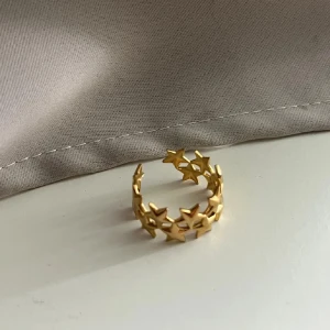 Guldfärgad ring med stjärndetaljer - Säljer en superfin guldfärgad ring med stjärndetaljer. Ringen har en öppen design vilket gör den justerbar och perfekt för alla tillfällen. Den glänsande ytan ger en lyxig känsla och stjärnorna ger en unik touch. Den är i rostfritt stål!!