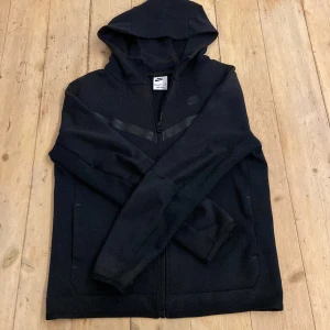 Nike tech fleece svart - Säljer min väl använda tech fleece, passar perfekt för någon som är cirka 160-165. Tröjan har små defekter där färgen har blivit lite brunaktig se på bild 4 finns på andra ärmen också. Går enkelt att fixa genom att färga om, skick 7,5-10