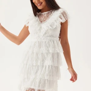Vit spetsklänning med volanger - Säljer en superfin vit spetsklänning med volanger och v-ringning. Klänningen har korta ärmar och flera lager av spets som ger en romantisk look. Perfekt för sommarens fester eller studenten! 💫 Har endast använts en gång och är i jättefint skick💖Nypris, 999kr