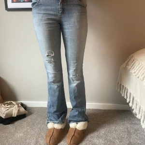 Blå bootcut jeans från Lee - Snygga blå bootcut jeans från Lee med slitna detaljer på benen. De har en klassisk femficksdesign och är tillverkade i en bomullsblandning med lite stretch för extra komfort. Perfekta för en avslappnad stil. De är lågmidjade och passar mig som är 175 ca