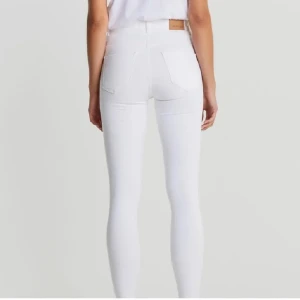 Vita skinny jeans - Snygga vita skinny jeans med hög midja. Perfekta för en stilren look. De har en klassisk design med fickor bak och knapp framtill.