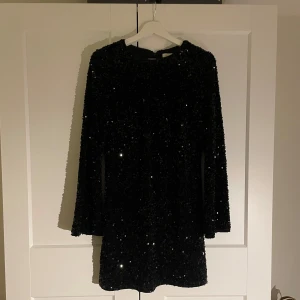 Svart glittrig klänning - Snygg svart klänning med glittriga paljetter. Klänningen har långa vida ärmar och en kort längd, perfekt för en utekväll! Inga defekter och tappar inga paljetter. Använd 1 gång. 🖤✨