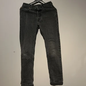 Svarta jeansbyxor från Levi's - Snygga svarta jeansbyxor från Levi's med klassisk femficksdesign och knappgylf. Byxorna har en rak passform och är perfekta för en stilren look. Levi's-logga på bakfickan ger en autentisk touch. Passar runt 155 till 167