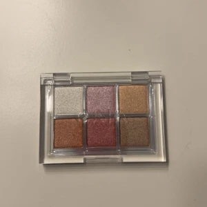 Disco Fever Eyeshadow Palette från Caia - Snygg ögonskuggspalett från Caia med sex olika nyanser: Diva, Flirty, Shameless, Groovy, Sequin och Last Dance. Perfekt för att skapa både subtila och dramatiska looks. Kompakt förpackning som är lätt att ta med sig.