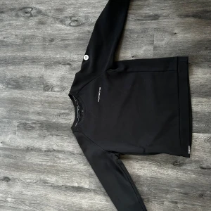 Sail Racing Porsche limiterad  - Snygg svart långärmad tröja från Sail Racing. Perfekt för en stilren look. Tröjan har en diskret logga på bröstet och en liten etikett vid fållen.