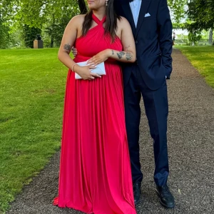 Röd balklänning lång med korsad hals  - Säljer en elegant röd långklänning med korsad halsdesign. Använd en gång på min bal! Super fint skick! Storleken passar alla då den är Onesize! Kan knytas på alla olika sätt! Denna klänningen fick mig att känna mig så fin på balen, hoppas nu på att den får någon annan att känna sig lika vacker på sin bal eller annan tillställning!🥰