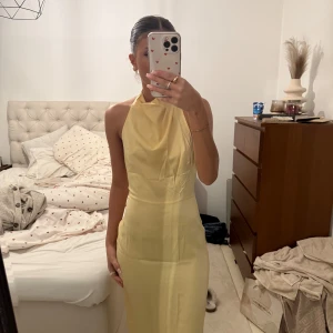 Gul Balklänning - Säljer en elegant gul halterneck klänning med öppen rygg. Perfekt för bal & bröllop. Kkäningen sitter som en xs/s, typ en lite större xs men lite mindre s. Materialet är i ungefär silke.