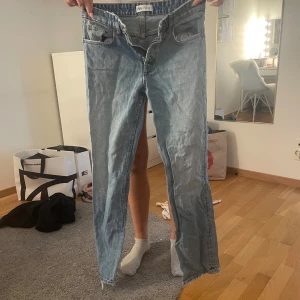 Ljusa jeans med slits - Snygga ljusblå jeans från Zara med slitsdetaljer på benen. De har en klassisk femficksdesign och råa kanter vid bensluten för en trendig look. Perfekta för en avslappnad stil.