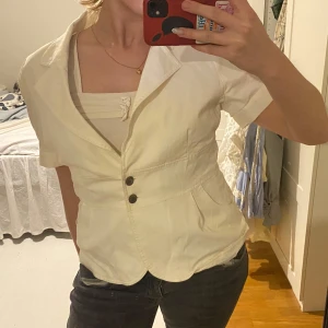 Vit kavaj med knappar - Säljer en vit kavaj med korta ärmar och två knappar framtill. Perfekt för en chic look. Kavajen har en klassisk krage och två fickor. Passar bra till både jeans och kjol❤️❤️