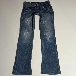 Blå bootcut jeans - Snygga blå bootcut jeans med slitna detaljer. De har en lågmidjad passform och klassisk femficksdesign. Perfekta för en avslappnad stil. Dom är lite smutsiga på framsidan men går att tvätta bort har inte försökt!