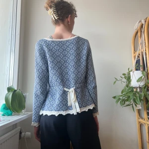 Rosebud Kofta - Fin mönstrad kofta med knytdetalj och volangdetaaljer vid ärmar