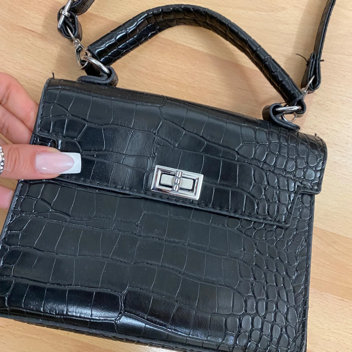 Svart handväska med krokodilmönster