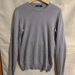 Grå tröja från J.Lindeberg - Snygg grå tröja från J.Lindeberg i en stilren design. Tröjan har långa ärmar och en rund halsringning. Perfekt för en stilren look.