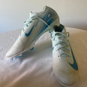 Nike fotbollsskor i ljusblått och vitt - Säljer mina Nike mercurial då jag inte kan ha modellen för den passade inte min fot… smått använda men skicket är som nytt! Storlek 44