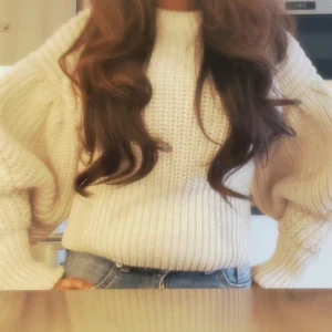 Beige stickad tröja med ballongärmar - Säljer en beige stickad tröja med ballongärmar och rund hals. Tröjan har en grovstickad struktur och är perfekt att styla med jeans för en avslappnad look.