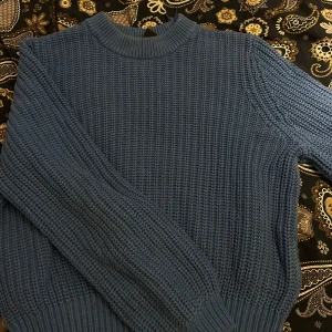 Blå stickad tröja från Lindex - Mysig blå stickad tröja från Lindex med rund halsringning och grovstickad struktur. Perfekt för kyligare dagar och enkel att matcha med olika outfits.