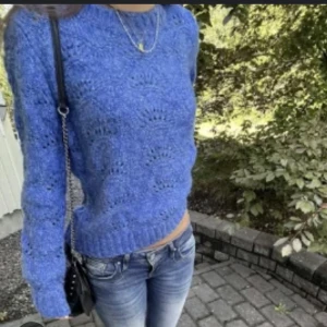 Blå stickad tröja från Zalando - Säljer en blå stickad tröja från Zalando med ett fint hålmönster. Tröjan har rund halsringning, långa ärmar och ribbade muddar vid ärmslut och nederkant. Perfekt för lager-på-lager och en mysig vardagslook.