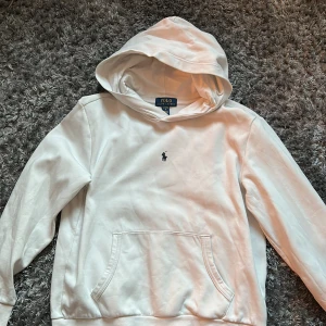 Vit hoodie från Polo Ralph Lauren - Säljer en klassisk vit hoodie från Polo Ralph Lauren med broderad logga på bröstet. Tröjan har huva och magficka. Tröjan passar för storlek mellan 158-168cm. Pris går att diskutera. Har du frågor så skriv!