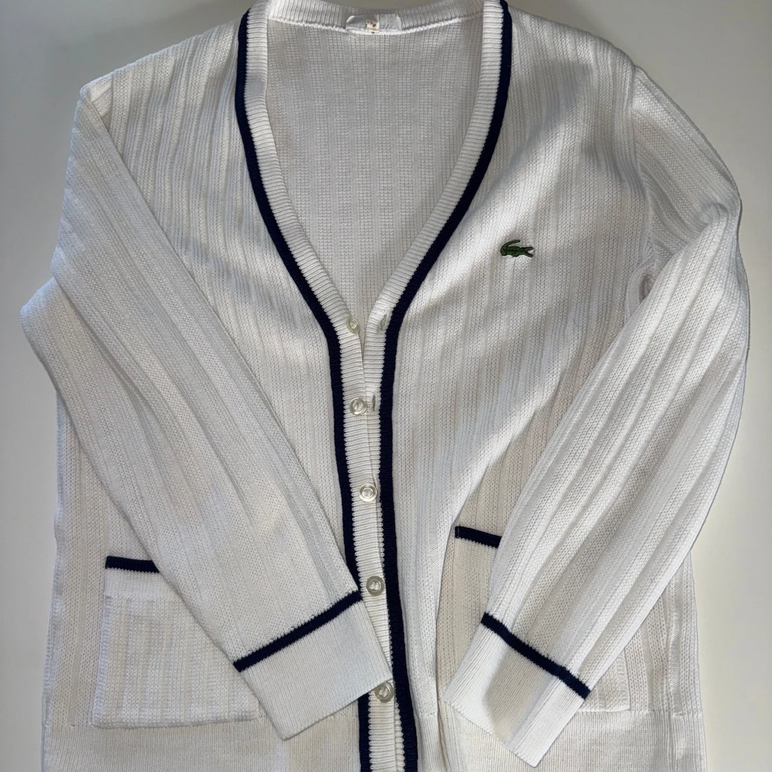 Vit kofta från Lacoste med mörkblå detaljer