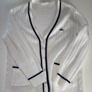 Vit kofta från Lacoste med mörkblå detaljer - Lacoste kofta med old monney känsla. Storlek S passar nog också M. Nyskick 
