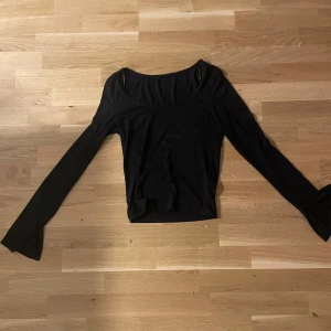 Svart långärmad topp från Gina Tricot - Säljer en svart långärmad topp från Gina Tricot med utsvängda ärmslut. Toppen har en rundad halsringning och är tillverkad i ett mjukt, stretchigt material som sitter snyggt på kroppen.