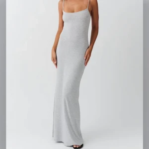 Ljusgrå långklänning med smala axelband - Säljer en stilren ljusgrå långklänning med smala axelband och figurnära passform. Klänningen har en minimalistisk design och är perfekt för dig som gillar enkel och snygg look💕