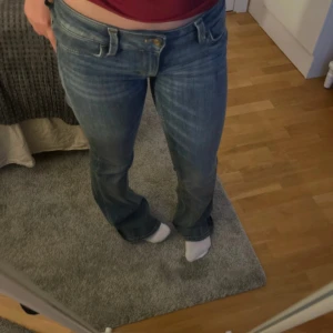 Blå bootcut jeans från cheap Monday  - Säljer ett par klassiska blå bootcut jeans från cheap Monday med  låg midja. Jeansen har fem fickor, slitningar och en snygg tvätt. Perfekta för dig som gillar en avslappnad och tidlös stil.
