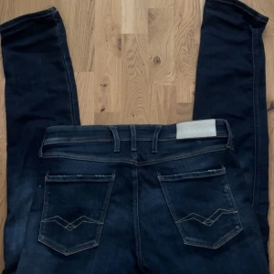 Replay Anbass - Säljer ett par mörkblå jeans från Replay med klassisk femficksdesign och snygga slitningar framtill. Storlek 32-34