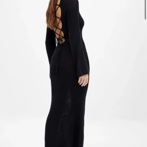 Svart lång stickad klänning med snörning i ryggen - Säljer en svart långklänning i stickat material med lång ärm och snygg öppen rygg med snörningsdetalj. Klänningen har en tight passform och är perfekt för dig som vill ha något stilrent men ändå unikt. Använd en gång 