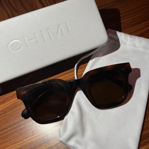 Bruna solglasögon från CHIMI i modell Tortoise - Snygga solglasögon från CHIMI i modellen Tortoise med brunmelerat mönster och fyrkantig form. Glasögonen har breda skalmar och mörka linser, perfekt för en trendig look. Kommer med originalfodral och påse.  Pris kan diskuteras🌸💕 