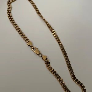 Kedjehalsband i guld - Snyggt halsband med platt kedjedesign i guldfärgad metall. Klassisk och stilren look som passar perfekt till att lyfta din outfit. Lås med karbinhake för extra säkerhet. Inte använd många gånger alls, är som ny. Är även i rostfrittstål.