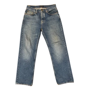 Blå jeansbyxor från Wole Jeansco - Klassiska blå jeansbyxor från Wole Jeansco med raka ben och fem fickor. Byxorna har normal passform, orangea sömmar och knappgylf. Perfekta för dig som gillar en tidlös jeansstil.