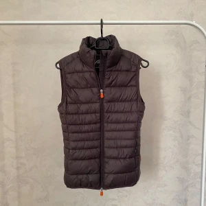 Brun dunväst från Save The Duck - Säljer en brun, ultralätt dunväst från Save The Duck. Sparsamt använd! Size 0 men passar mig med storlek S