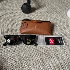 Svarta solglasögon från Ray-Ban - Klassiska svarta solglasögon från Ray-Ban med svart båge och mörka glas. Kommer med original brunt fodral och Ray-Ban märkning på glaset. Perfekt accessoar för soliga dagar. Skriv för mer info🥂👌