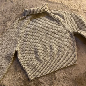 Grå stickad tjock tröja  - Säljer en grå stickad tröja med ribbade detaljer och lång ärmar, perfekt för lager-på-lager-stil. Supermjuk och skön att ha på sig! perfekt för sommarkvällar.