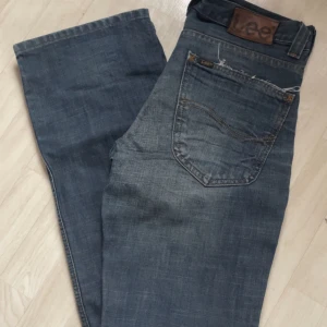 Blå jeansbyxor från Lee - Grå/blå low waist jeans från Lee med femficksdesign, utsvängda från knäna och ner, skit snygga, super fint skick men ett litet hål på högra knäet