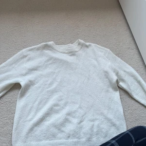 Vit stickad tröja - Mysig vit stickad tröja med rund halsringning och långa ärmar. Perfekt för lager-på-lager och enkel att matcha med olika outfits. Klassisk och stilren design som passar till många tillfällen. Storlek 160