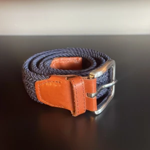 Blått flätat bälte från Jack & Jones - Snyggt blått flätat bälte från Jack & Jones med detaljer i brunt skinn och silverspänne. Bältet är 90 cm och köpt från Jack Jones i butik. Nypris 600kr. Hör av dig vid mer frågor