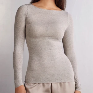 Ljusgrå långärmad topp i bomull - Säljer en ljus beige/grå, tight långärmad topp i kashmir. Toppen har rund halsringning och en slät, enkel design utan synliga detaljer. Perfekt basplagg att styla till olika outfits.