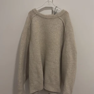 Beige stickad tröja från Pull&Bear - Mysig beige stickad tröja från Pull&Bear i storlek XS. Tröjan har en avslappnad passform, rund halsringning och ribbade muddar vid ärmslut och nederkant. Perfekt för lager-på-lager och chill dagar.