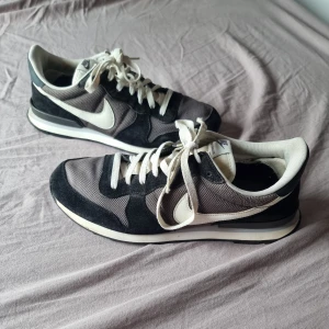 Nike Internationalist svarta sneakers - Nike Internationalist sneakers i svart och grått med vita detaljer och snörning. Tecken på användning.