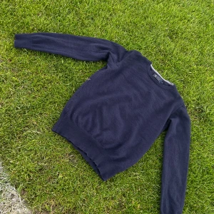 Mörkblå merinoullströja från Riley - Snygg mörkblå tröja från Riley i mjuk och tunn merinoull. Klassisk rund halsringning, ribbade muddar och lång ärm. Perfekt för lager-på-lager och passar till både jeans och chinos. Enkel och stilren design utan mönster. M i barnstorlek och XS i men. Vill bli av med den pruta på