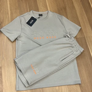 Ljusgrå t-shirt och shorts från Hugo boss - Säljer detta helt nya Hugo boss dress med T-shirt och shorts som är perfekt för sommaren😃. Båda plaggen är i storlek M.