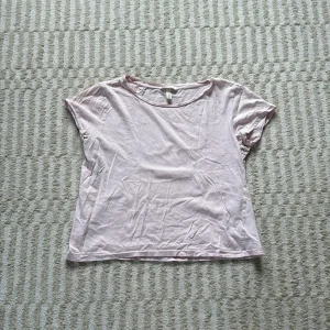 Ljusrosa t-shirt från H&M - En basic ljusrosa t-shirt från H&M i mjuk bomull. Modellen är klassisk med rund halsringning och korta ärmar. Perfekt till jeans eller shorts för en chill look.