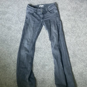 Grå bootcut jeans med fickdetaljer - Snygga grå jeans med bootcut-modell och coola fickor både fram och bak. Jeansen har dubbla knappar i midjan och klassiska sömmar. Perfekta för dig som gillar en avslappnad men ändå trendig look. 