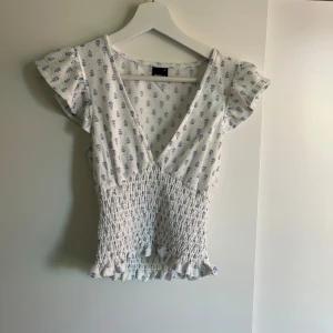 Vit blå blus från gina - Super söt sommar blus från Gina tricot som är använd fåtal gånger och är som i nyskick. Blusen är i storlek xs. Säljer för att jag gör en stor garderobs rensning och denna tyvärr inte kommit till så mycket användning för min del 🩷 