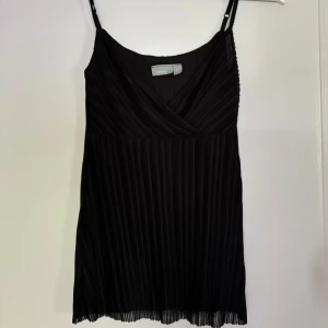 Svart plisserad linnetopp från Lindex - Snygg svart linnetopp från Lindex med smala axelband och omlott-ringning. 